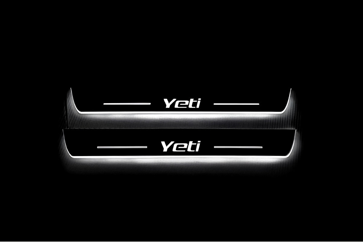 Two long door sill plates with Yeti lettering and edges illuminated in white, straight-on view on a dark background.