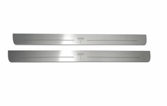 Two long silver-finished door sill plates with Tesla T emblems lettering on a light background, straight-on view.