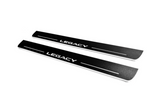 Two long black-finished door sill plates with white Legacy lettering and horizontal lines, angled view on a white background.