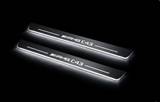 Two long door sill plates with AMG C43 lettering and edges illuminated in white, angled view on a dark background.