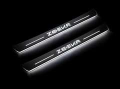 Two long door sill plates with Zeekr lettering and edges illuminated in white, angled view on a dark background.