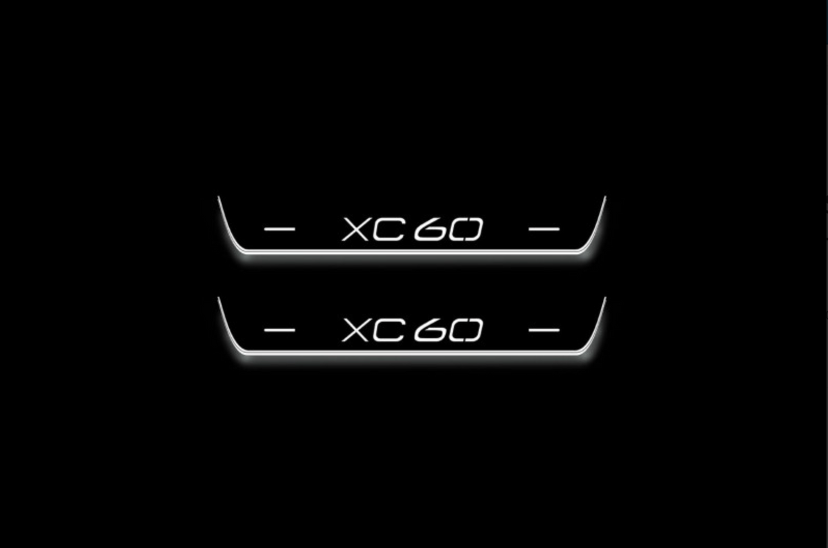 Two short door sill plates with XC60 lettering and edges illuminated in white, straight-on view on a dark background.
