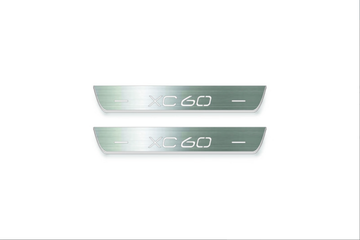 Two short silver-finished door sill plates with XC60 lettering on a light background, straight-on view.
