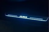 One long door sill plate with Auris lettering and horizontal lines illuminated pale blue against a dark background.