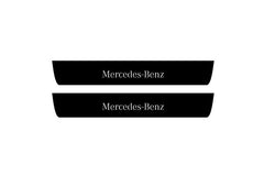 Catalog illustration of two black front door sill plates with Mercedes-Benz lettering.
