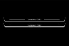 Two long door sill plates with Mercedes-Benz lettering and edges illuminated in white, straight-on view on a dark background.
