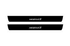 Catalog illustration of two black front door sill plates with Mazda3 lettering.