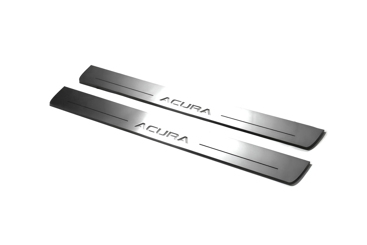 Two long silver-finished door sill plates with Acura lettering on a light background, angled view.