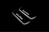 Two short door sill plates with Acura lettering and edges illuminated in white, angled view on a dark background.
