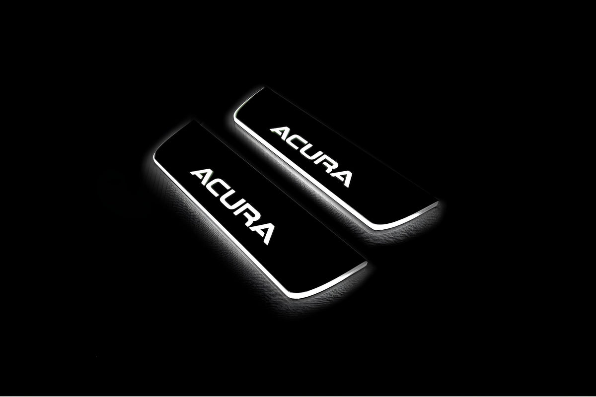 Two short door sill plates with Acura lettering and edges illuminated in white, angled view on a dark background.
