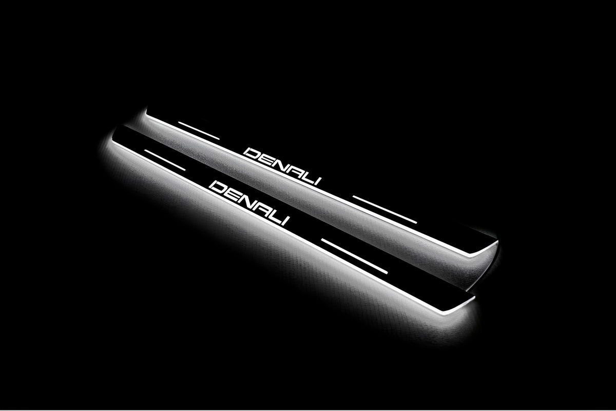 Two short door sill plates with Denali lettering and edges illuminated in white, angled view on a dark background.