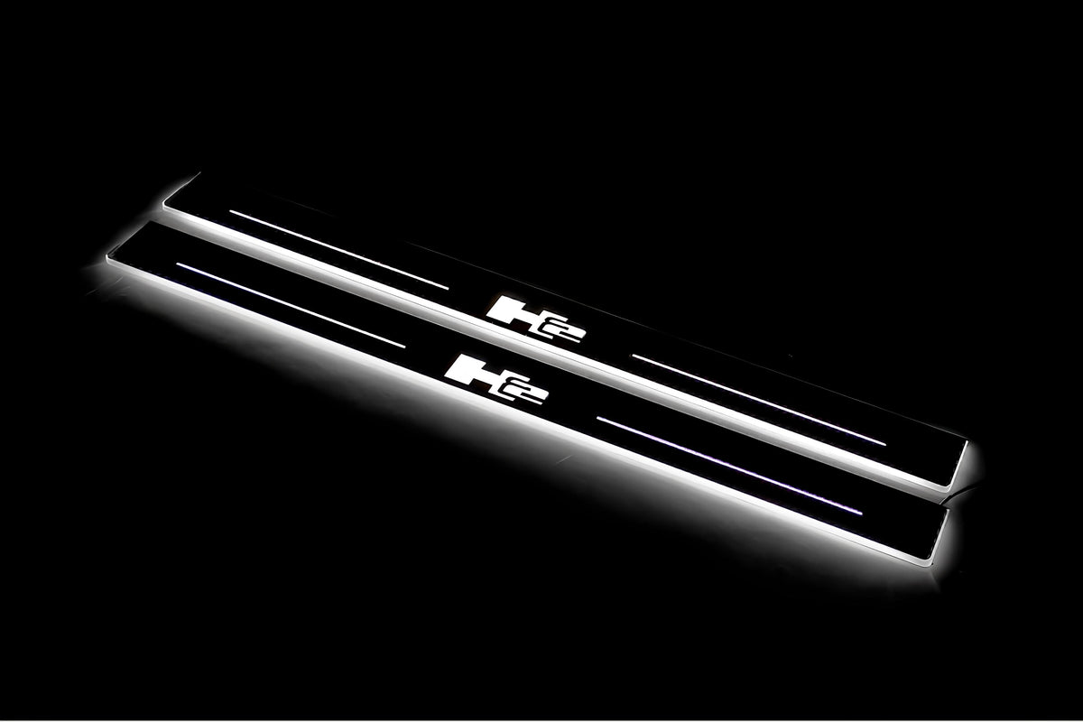 Two long door sill plates with H2 lettering and edges illuminated in white, angled view on a dark background.