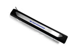 Black molded threshold trim with a silver insert bearing blue M Performance lettering and an attached wire, angled view.
