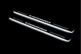 Two long door sill plates with Camaro lettering and edges illuminated in white, angled view on a dark background.