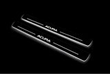 Two long door sill plates with Acura lettering and edges illuminated in white, angled view on a dark background.