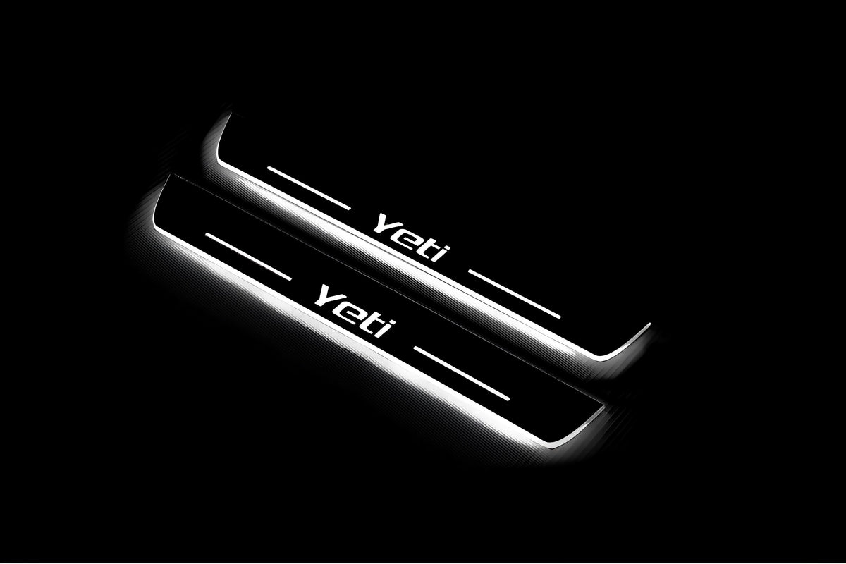 Two long door sill plates with Yeti lettering and edges illuminated in white, angled view on a dark background.