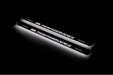 Two long door sill plates with M Performance lettering and edges illuminated in white, angled view on a dark background.