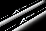 Close-up of A-Spec lettering and illuminated edges on door sill plates against a dark background.