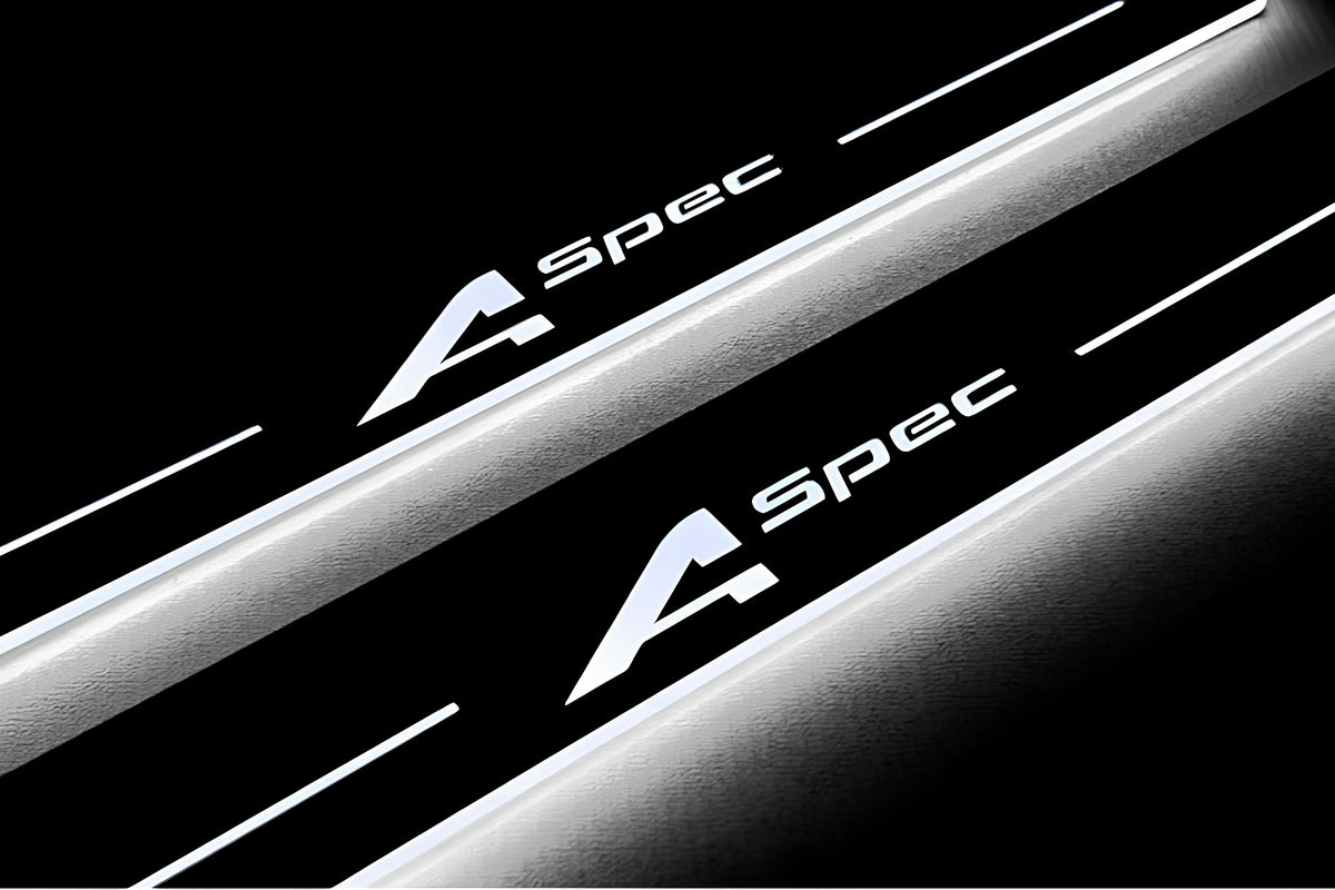 Close-up of A-Spec lettering and illuminated edges on door sill plates against a dark background.