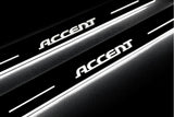 Close-up of Accent lettering and illuminated edges on door sill plates against a dark background.