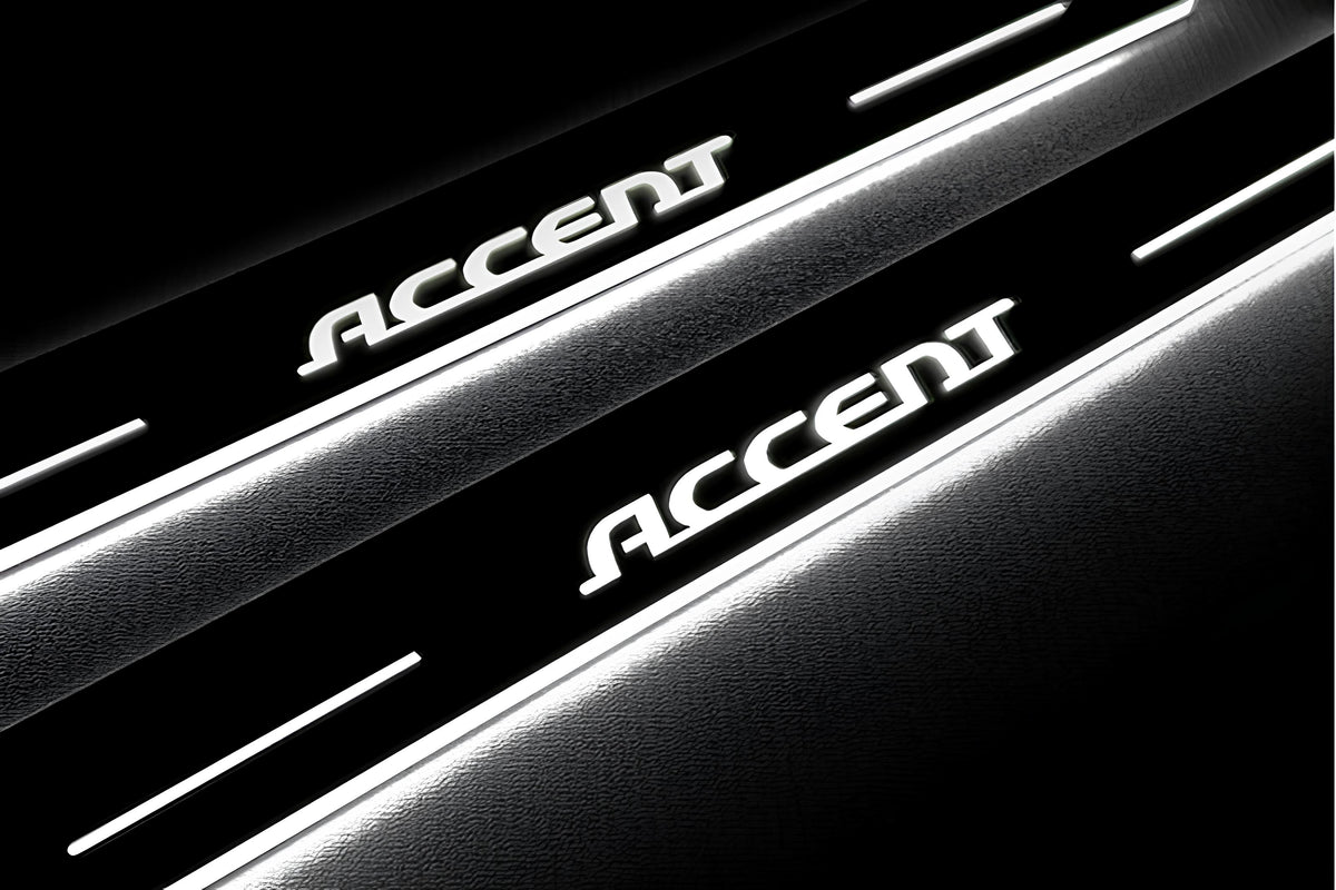 Close-up of Accent lettering and illuminated edges on door sill plates against a dark background.