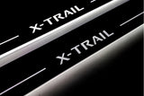 Close-up of X-Trail lettering and illuminated edges on door sill plates against a dark background.
