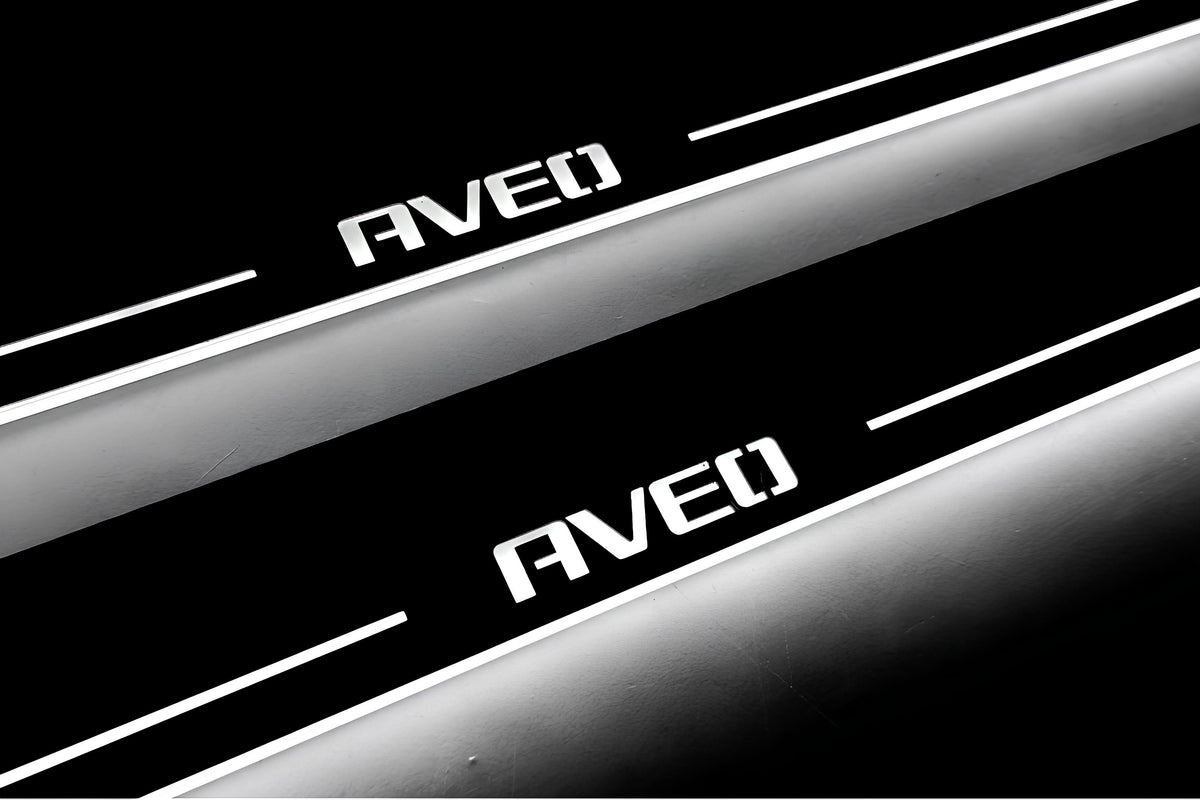 Close-up of Aveo lettering and illuminated edges on door sill plates against a dark background.