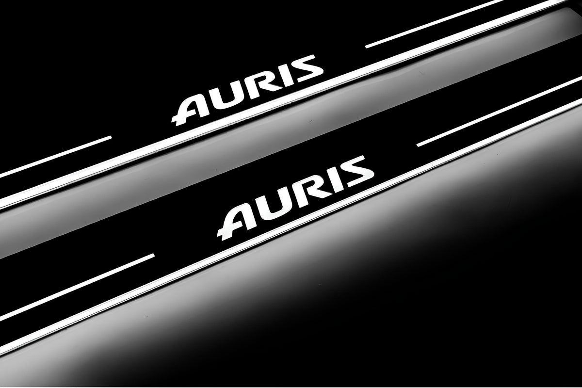 Close-up of Auris lettering and illuminated edges on door sill plates against a dark background.