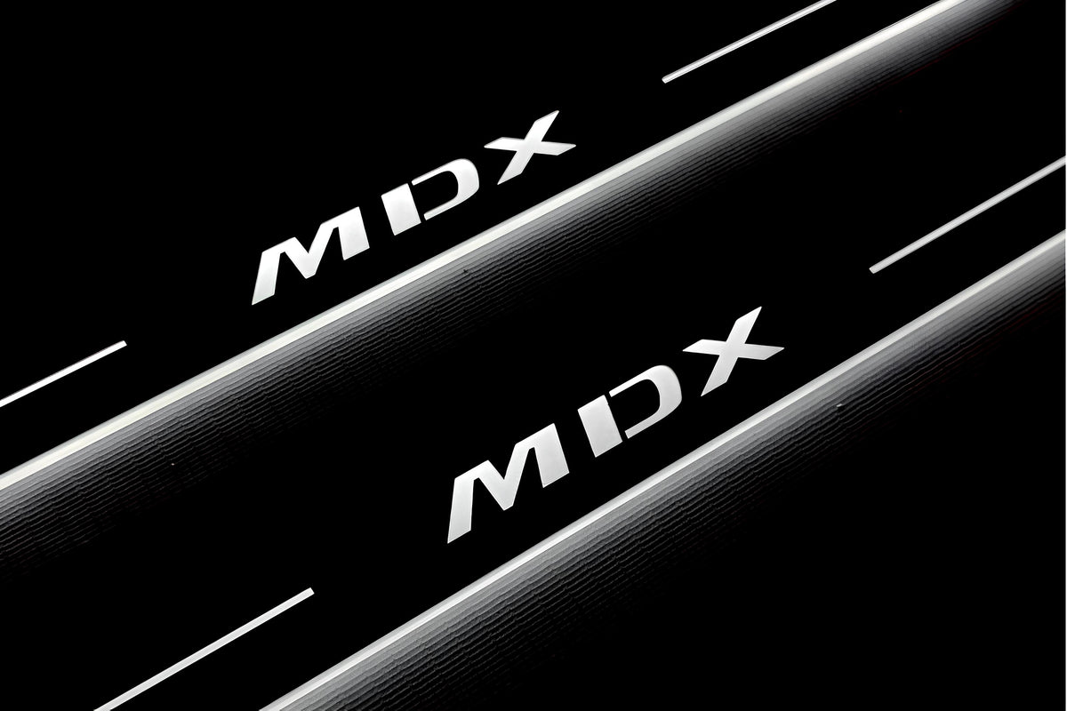 Close-up of MDX lettering and illuminated edges on door sill plates against a dark background.
