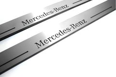 Close-up of Mercedes-Benz lettering and linear slots in silver-finished door sill plates.
