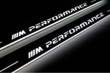 Close-up of M Performance lettering and illuminated edges on door sill plates against a dark background.