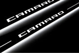 Close-up of Camaro lettering and illuminated edges on door sill plates against a dark background.