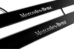 Close-up of black door sill plates with white Mercedes-Benz lettering.