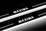Close-up of Maxima lettering and illuminated edges on door sill plates against a dark background.