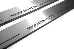 Close-up of AMG lettering and linear slots in silver-finished door sill plates.