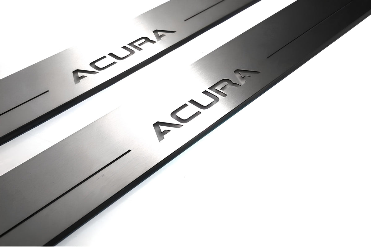 Close-up of Acura lettering and linear slots in silver-finished door sill plates.
