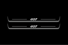 Two long door sill plates with 407 in italic lettering lettering and edges illuminated in white, straight-on view on a dark background.