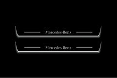 Two long door sill plates with Mercedes-Benz lettering and edges illuminated in white, straight-on view on a dark background.