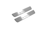Two short silver-finished door sill plates with X-Trail lettering on a light background, angled view.