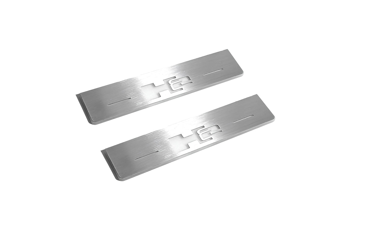 Two short silver-finished door sill plates with H2 lettering on a light background, angled view.