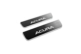 Two short reflective dark door sill plates with white Acura lettering on a white background, angled view.