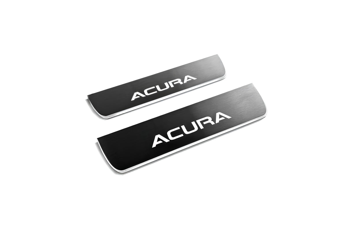 Two short reflective dark door sill plates with white Acura lettering on a white background, angled view.