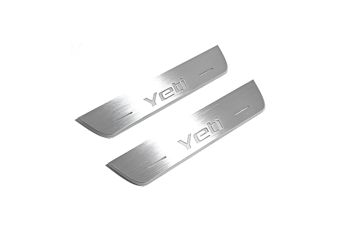 Two short silver-finished door sill plates with Yeti lettering on a light background, angled view.