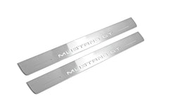 Two long silver-finished door sill plates with Mustang GT lettering on a light background, angled view.