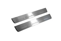Two long silver-finished door sill plates with Mercedes-Benz lettering on a light background, angled view.
