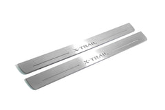 Two long silver-finished door sill plates with X-Trail lettering on a light background, angled view.
