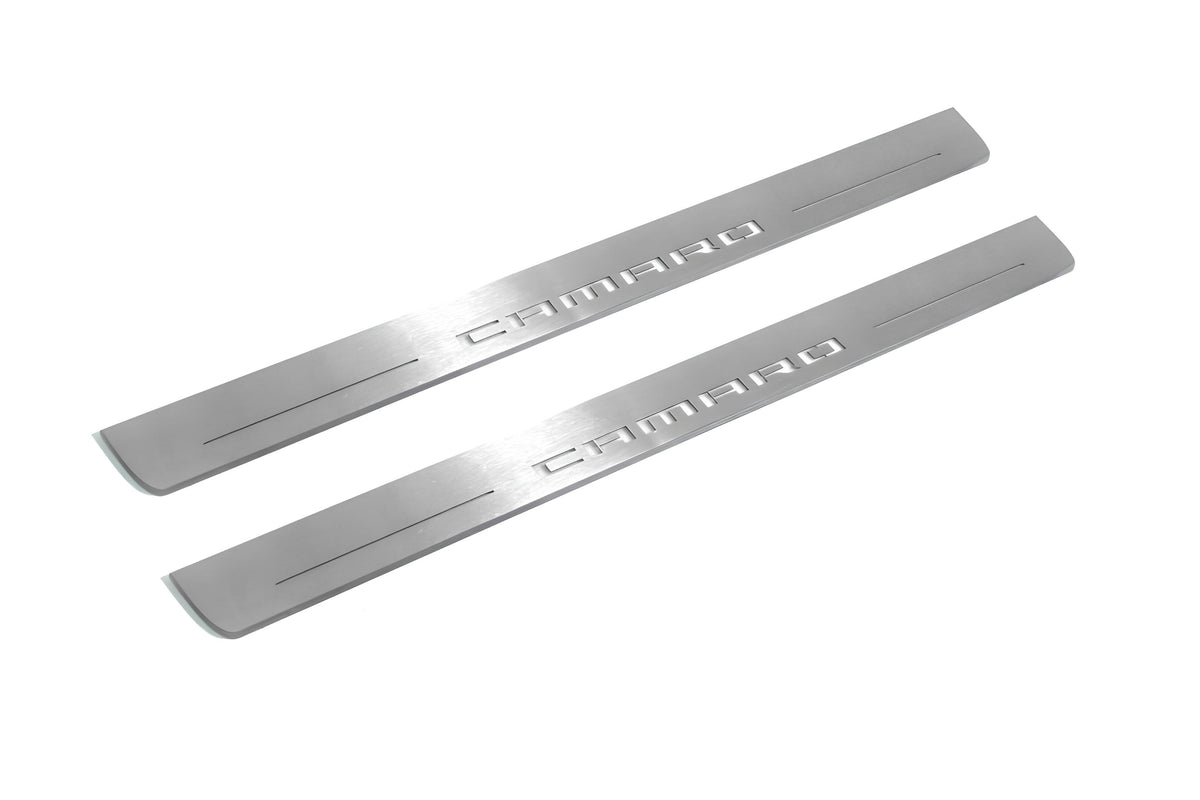 Two long silver-finished door sill plates with Camaro lettering on a light background, angled view.