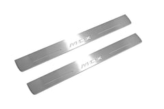 Two long silver-finished door sill plates with MDX lettering on a light background, angled view.