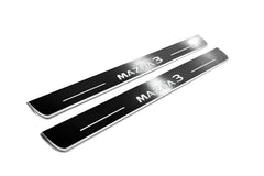 Two long silver-finished door sill plates with Mazda3 lettering on a light background, angled view.