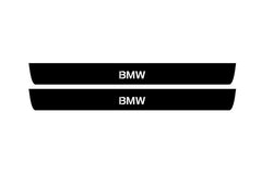 Catalog illustration of two black front door sill plates with BMW lettering.